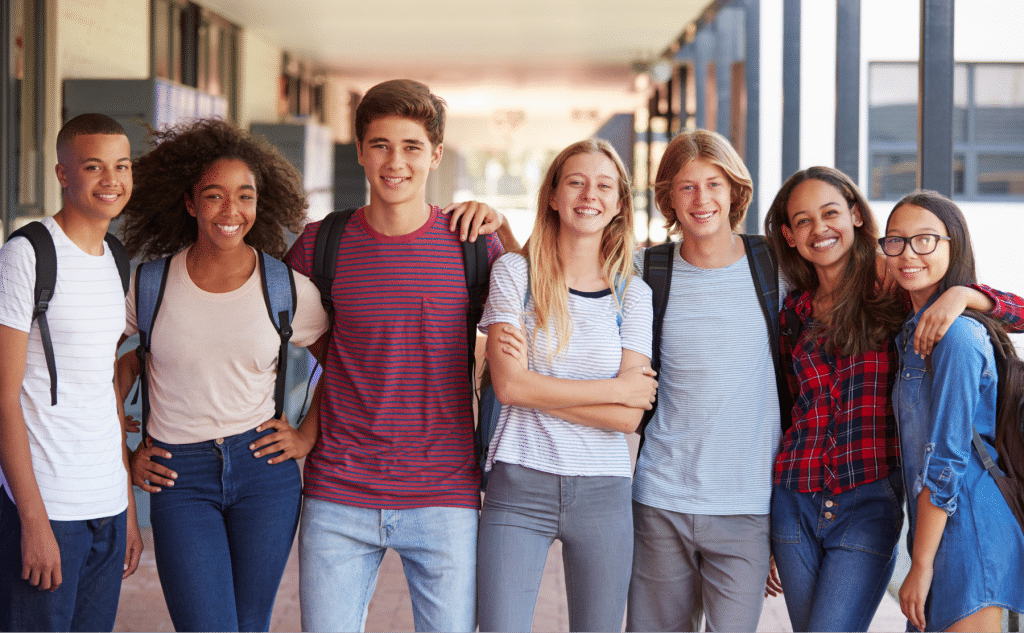 group of teenage classmates standing outside of school